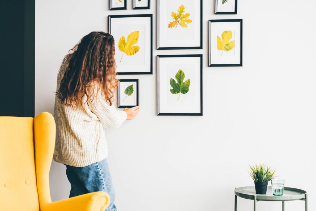 Woman hanging picture frame on wall in new house.
